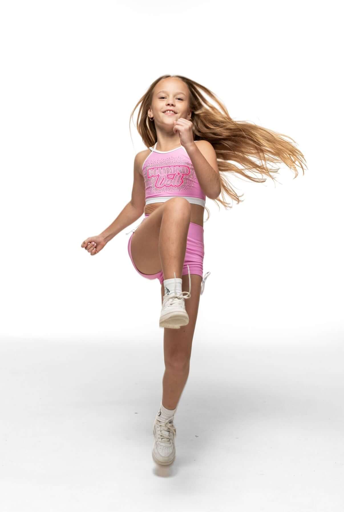 Girl wearing Bubblegum Sky Crop, showcasing criss-cross straps and playful movement in vibrant pink.