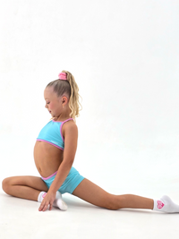 Girl performing a split in Blue Crush - Crop activewear set featuring baby blue and pink trim.