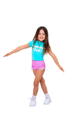 Child wearing a Blue Sherbet Puff Print Baby Tee with Diamond Doll logo and pink shorts, posing playfully.