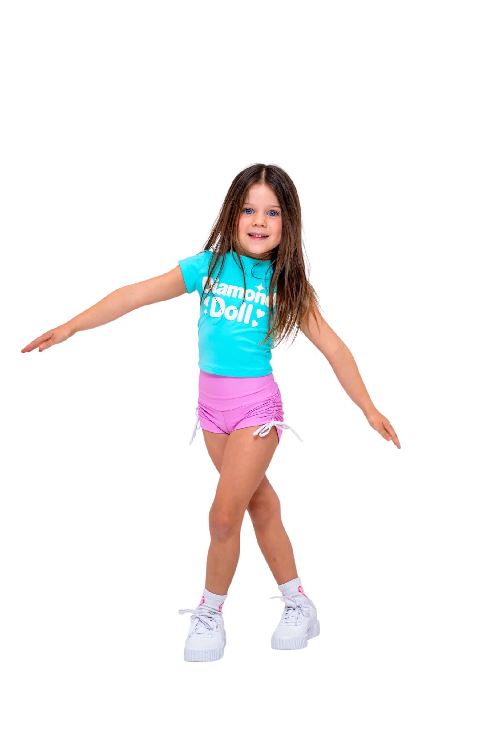 Child wearing a Blue Sherbet Puff Print Baby Tee with Diamond Doll logo and pink shorts, posing playfully.