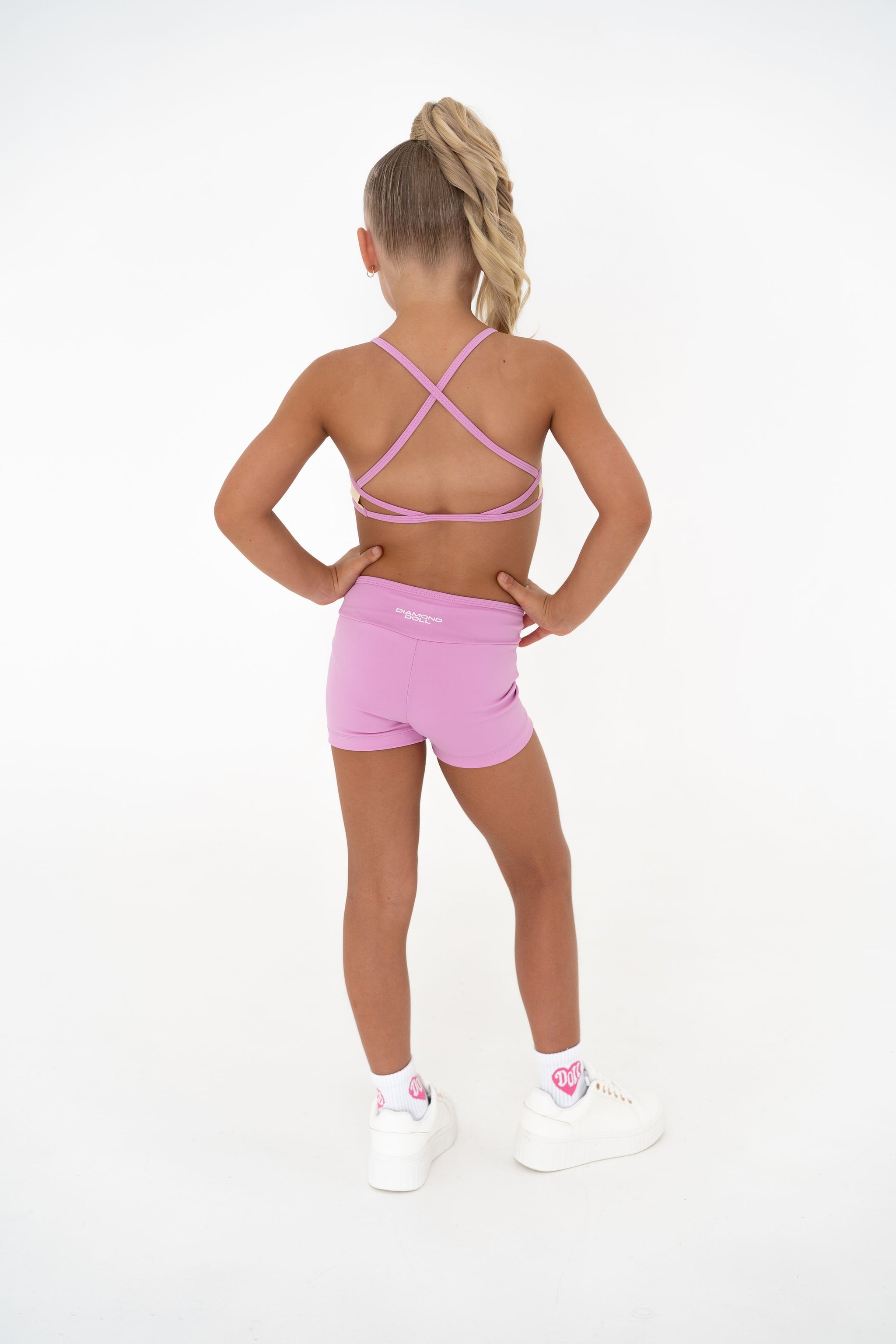Pink Lemonade – Crop activewear set shown from the back, featuring pastel pink shorts and supportive straps.