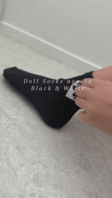Doll Socks (B&W) being worn, showcasing their soft black and white design on a foot.